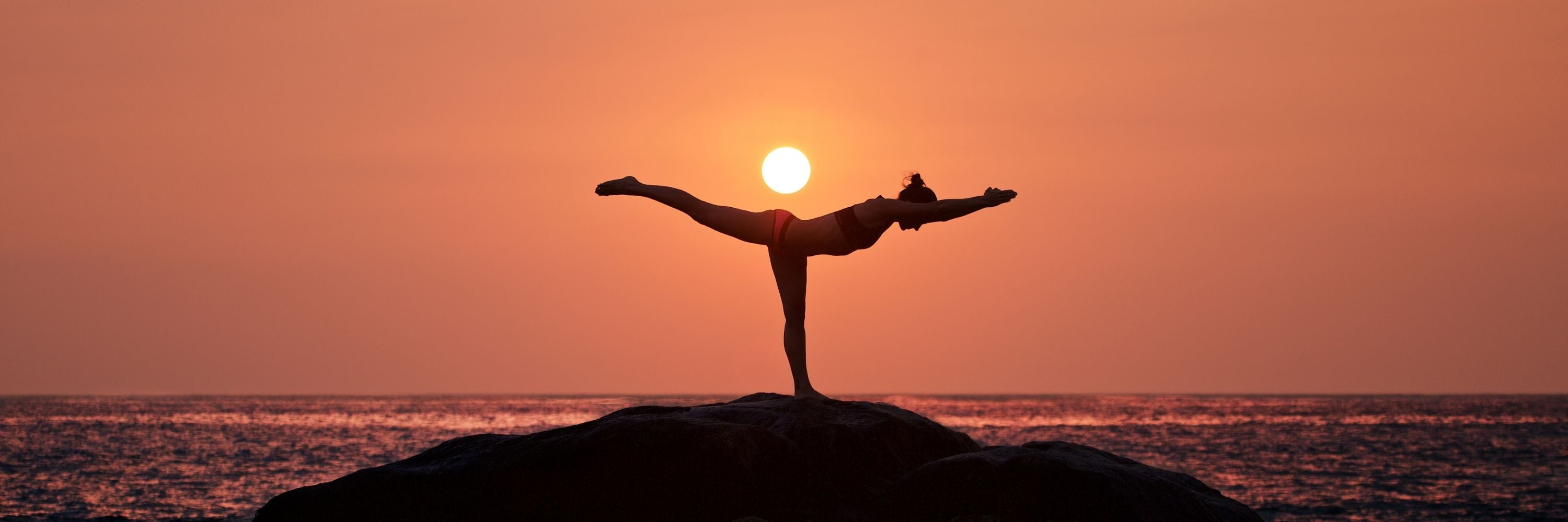 Woman doing yoga on a beach at sunset